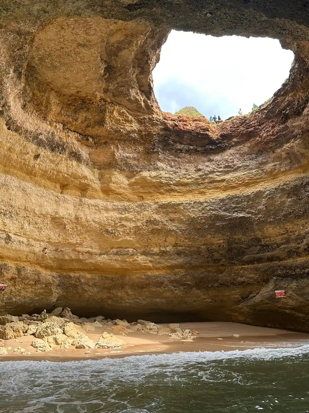 The banded rock dome of the cave above its sandy floor