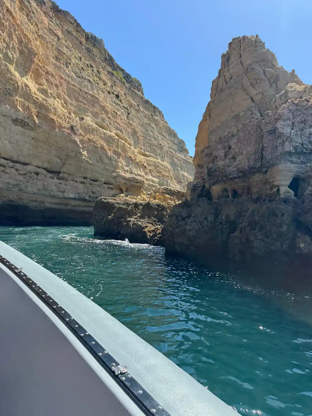 The boat rail alongside a jagged cliff and deep green water