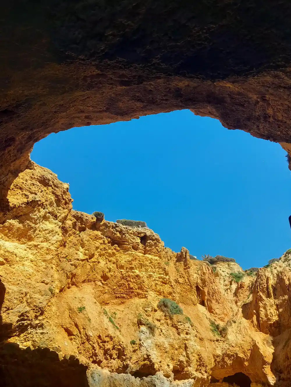 A broad arch of orange rock framing the open sea