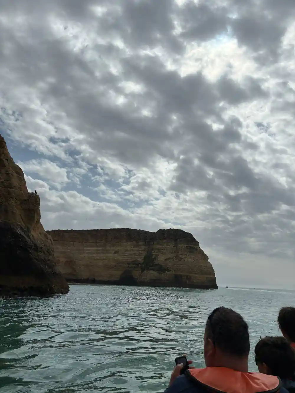 A cliff headland under heavy cloud seen from the boat