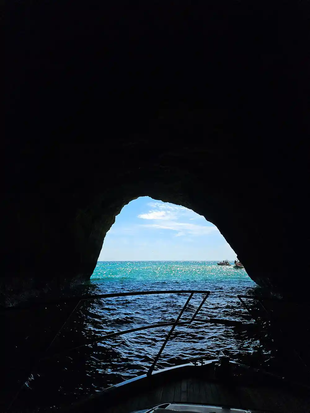 The dark interior of a cave looking out through the arch to open sea
