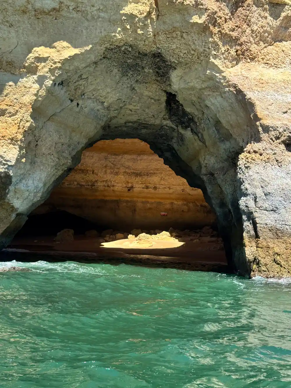 The dark mouth of a large cave with a sandy floor inside