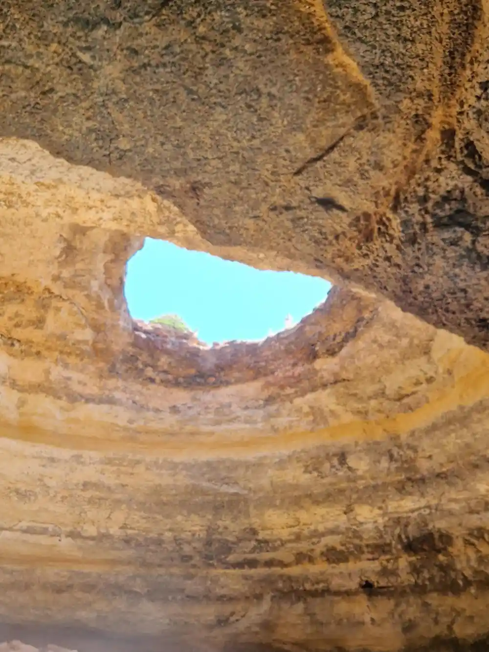 Daylight through the roof opening onto the dark cave wall