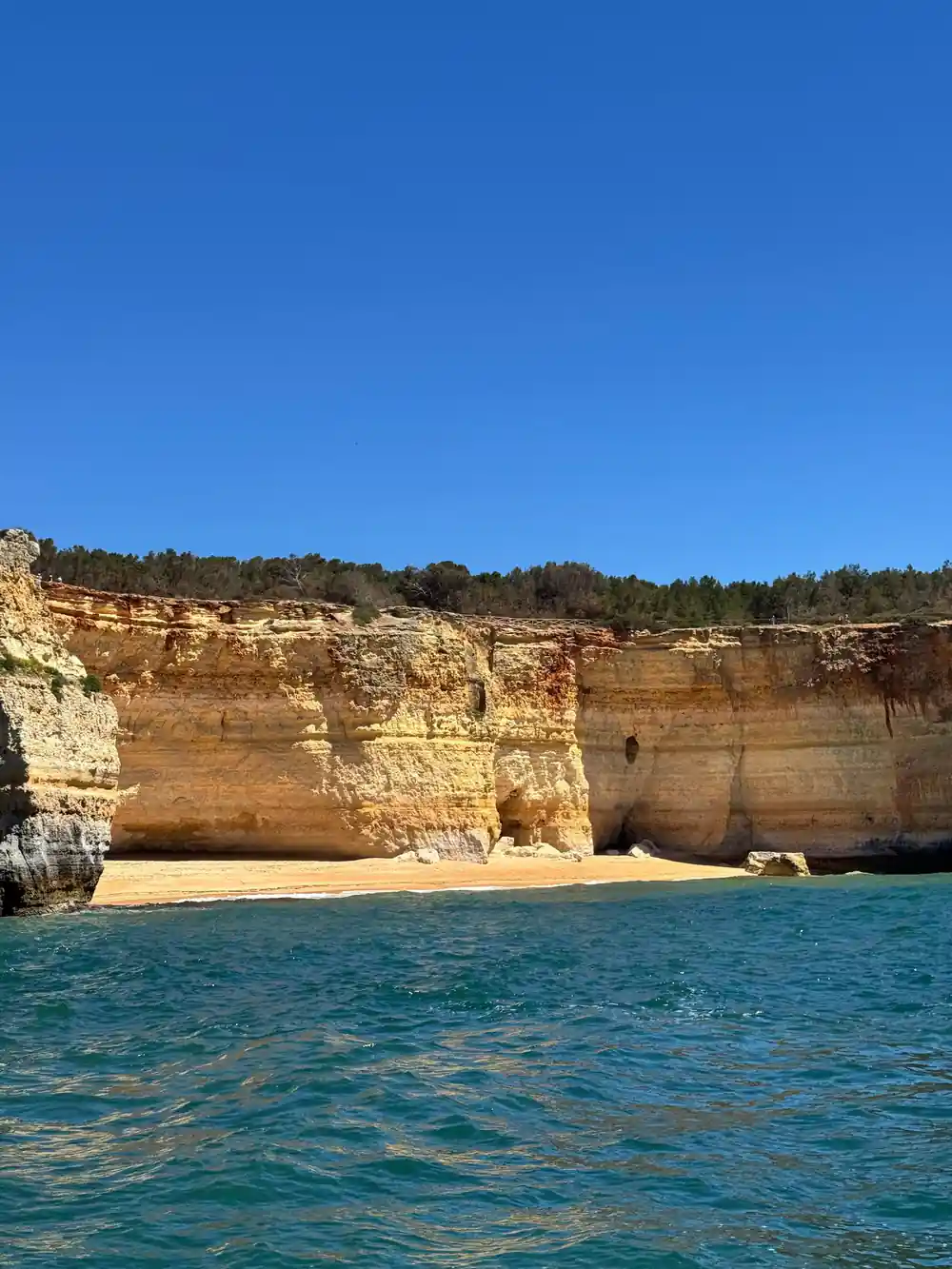 Layered gold cliffs above a small beach and clear water