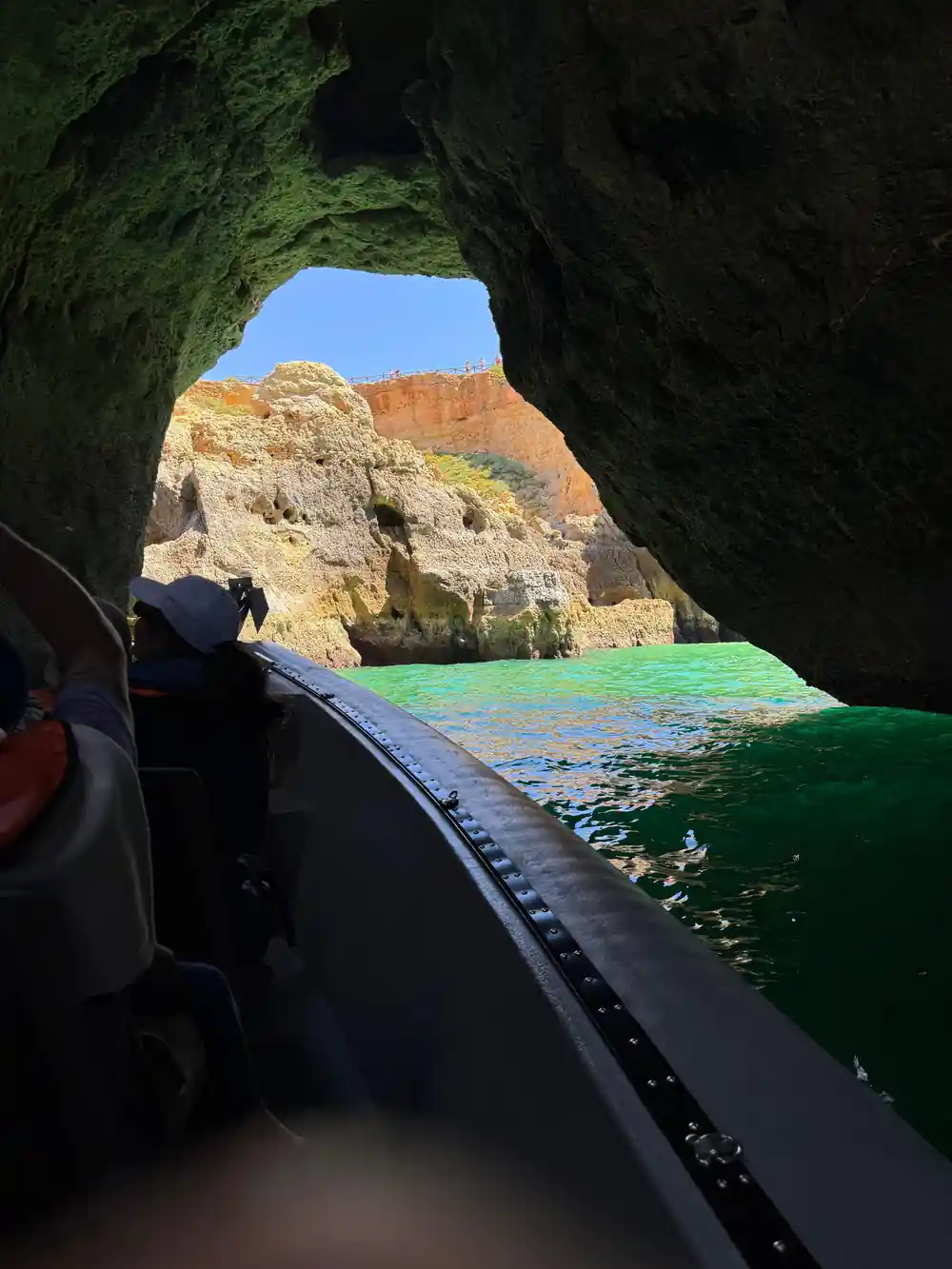 Looking out of a cave mouth from a boat towards the cliffs
