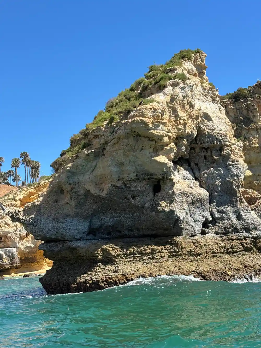 A pale rock headland with a cave mouth at the waterline