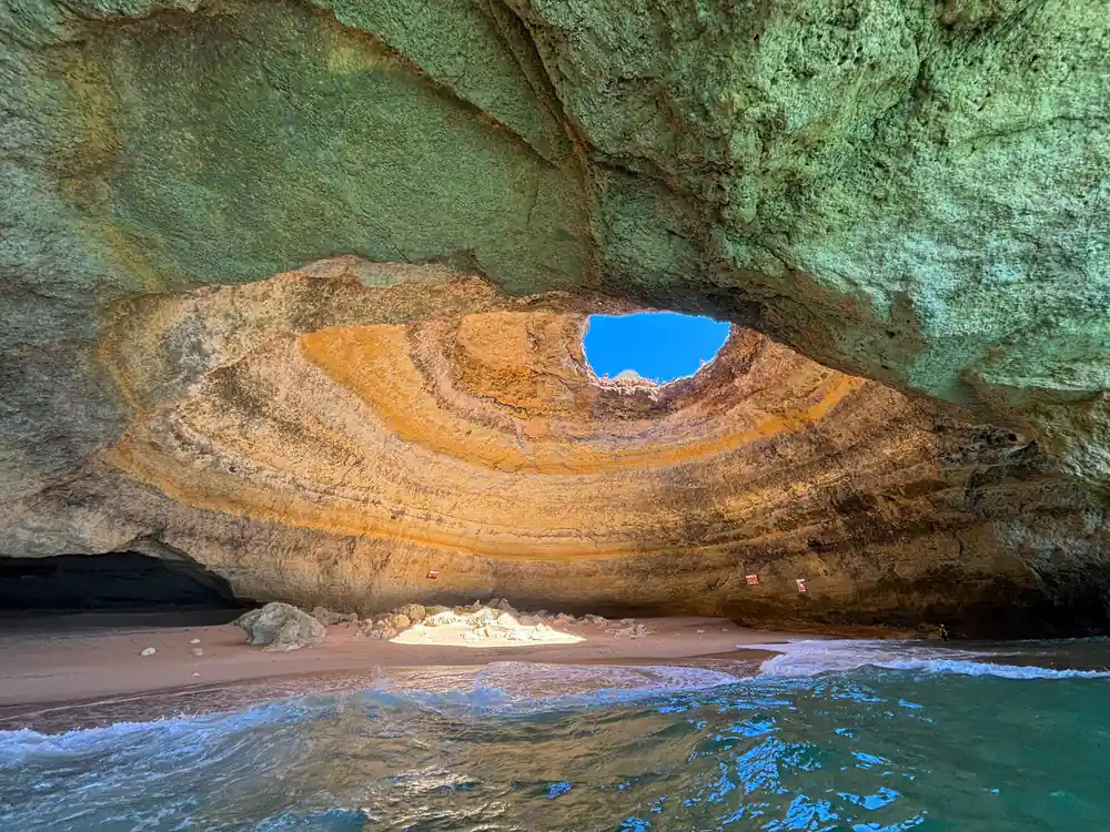 The roof opening above the sand with waves washing in
