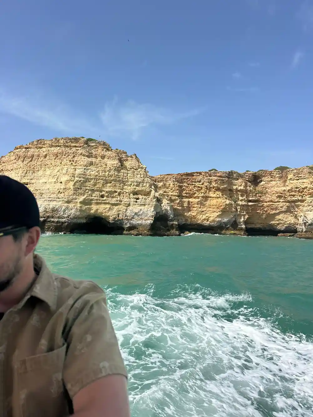 A skipper at the helm with the cliff coast behind him