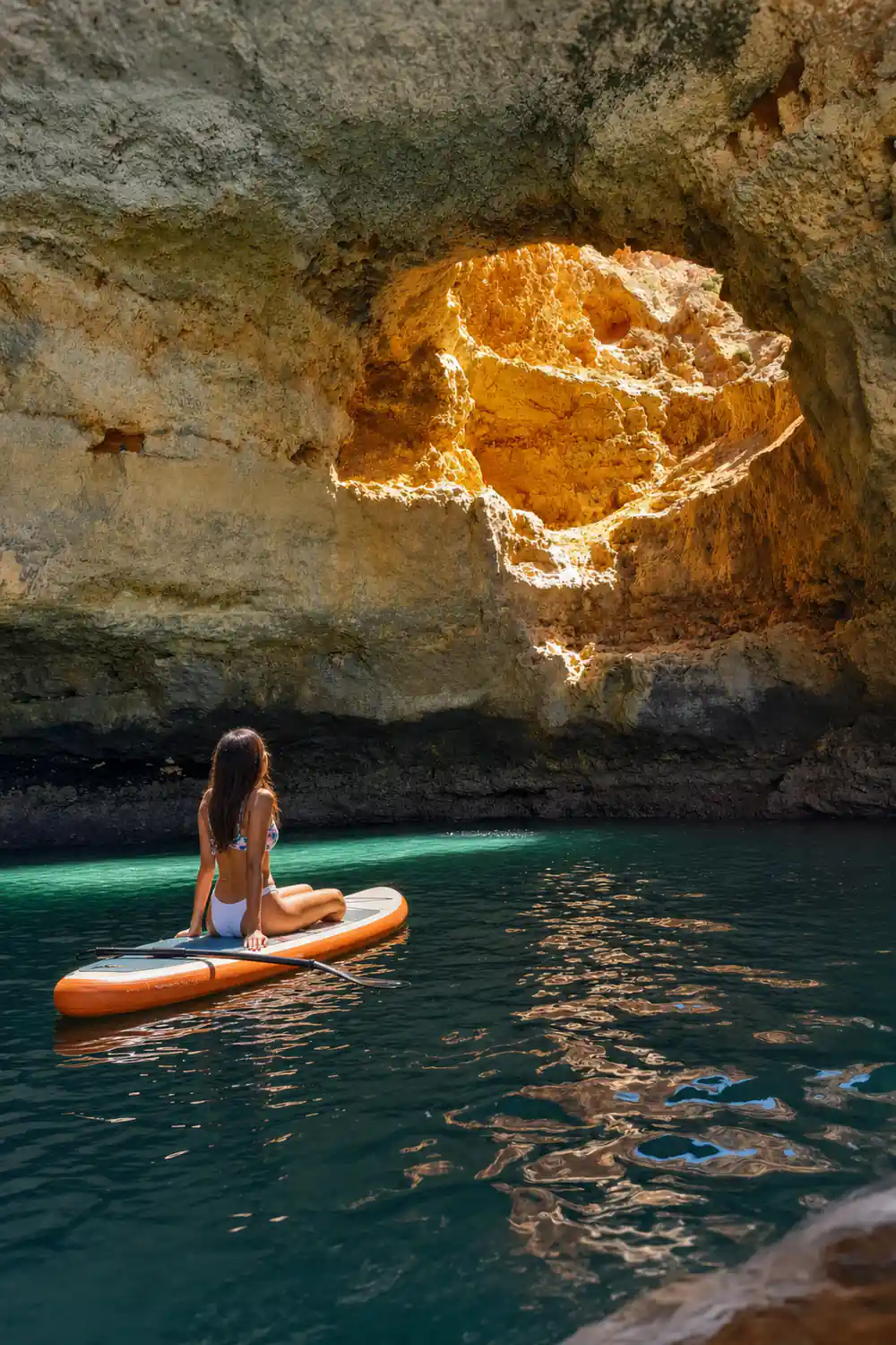 Sunlight catching the roof of a cave above still green water
