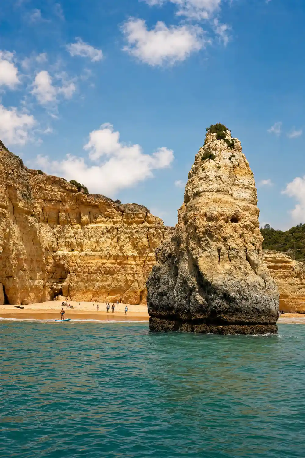 A tall rock stack standing on a beach below the cliffs