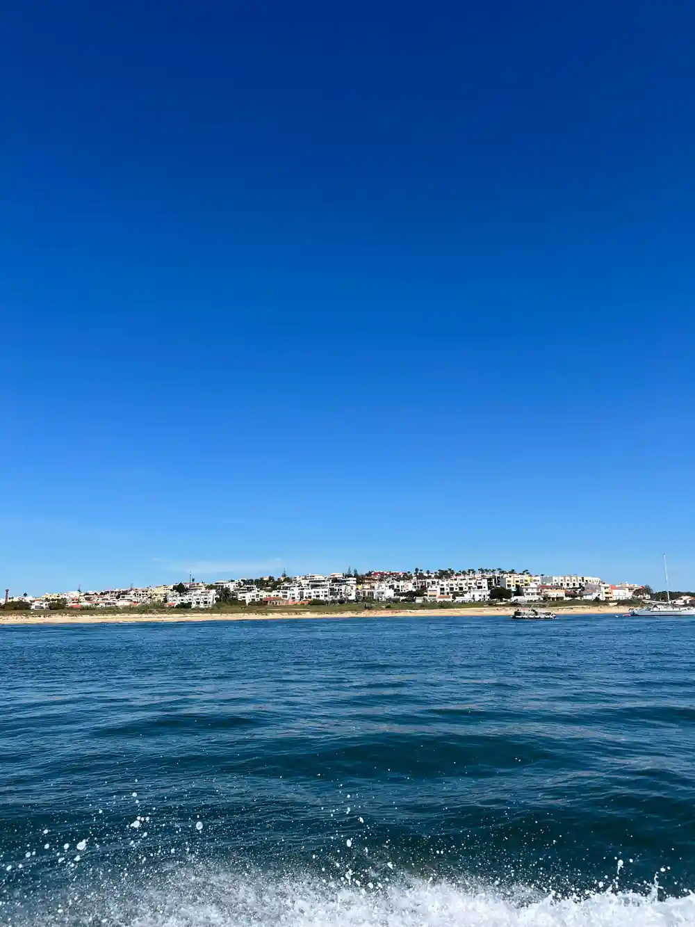 A white town along the shore across flat blue water