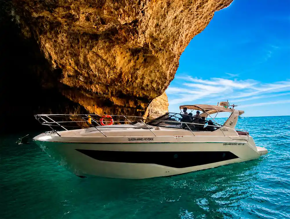 The yacht alongside a tall orange cliff face