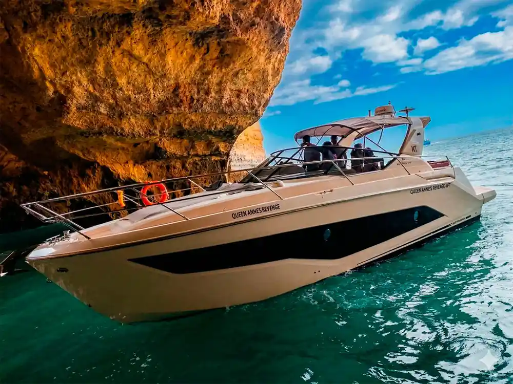 The yacht framed by the orange rock of the cave mouth