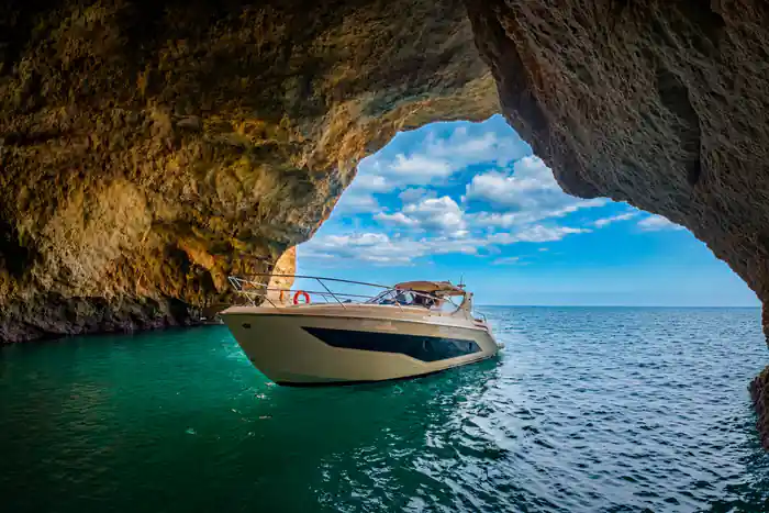 A yacht at the mouth of a sea arch on turquoise water