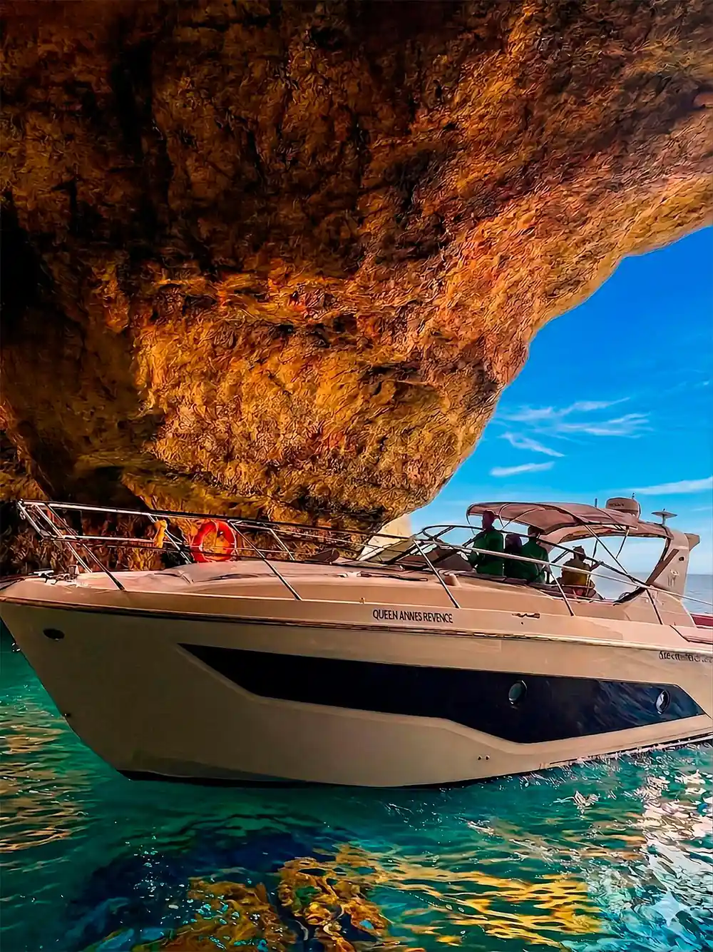 The yacht under the overhanging rock at the cave entrance
