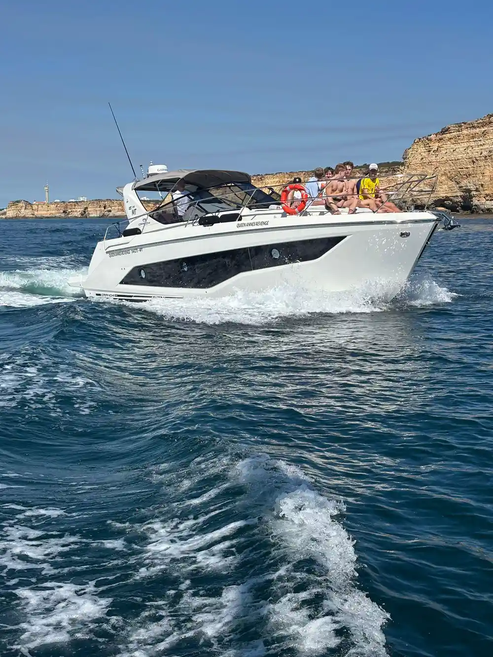 The yacht under way with the coast and other boats behind